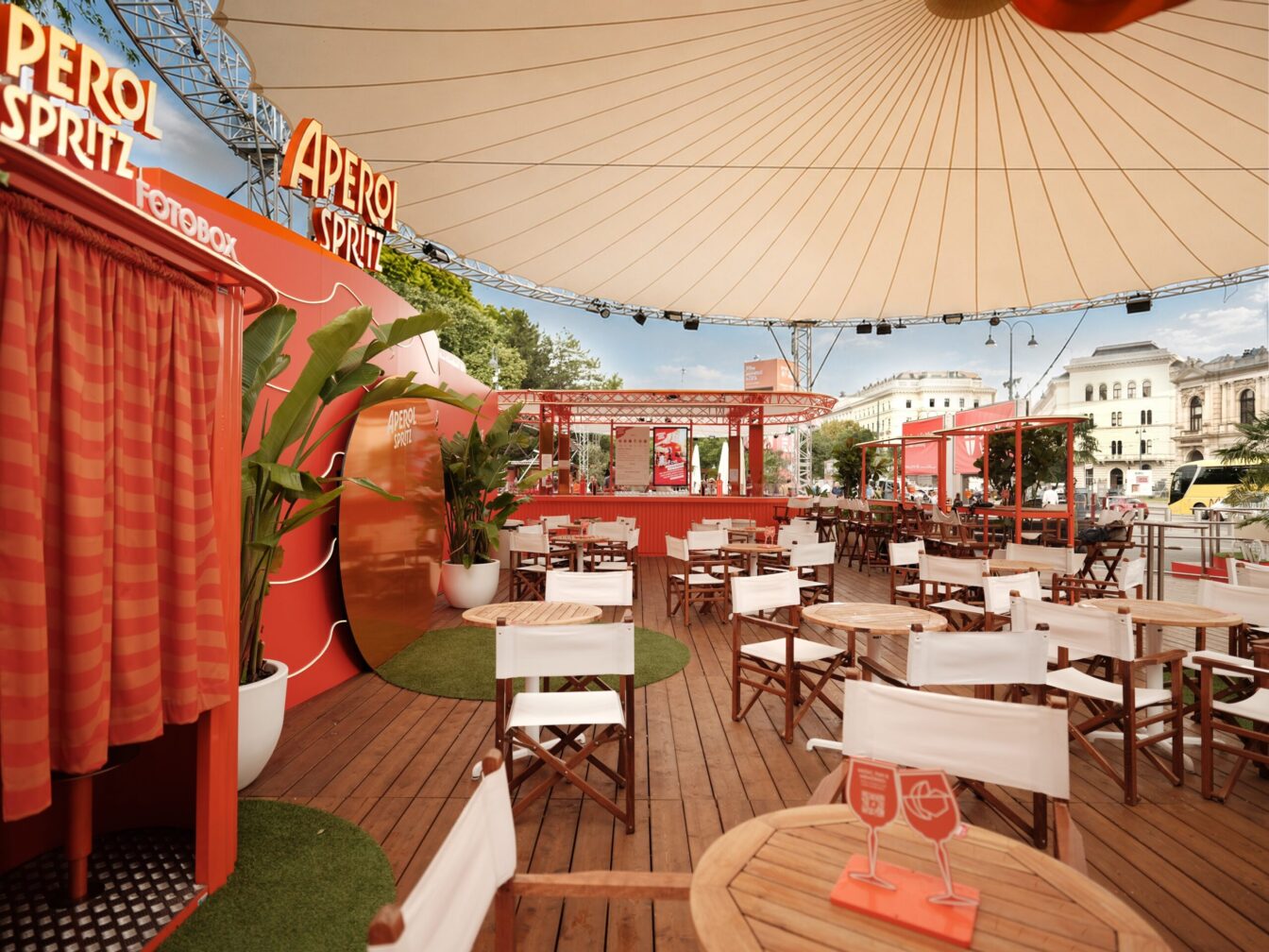Tische, Sesseln, Aperol Spritz Deko und Blick auf die Bar der Aperol Spritz Piazza am Rathausplatz im 1. Bezirk in Wien