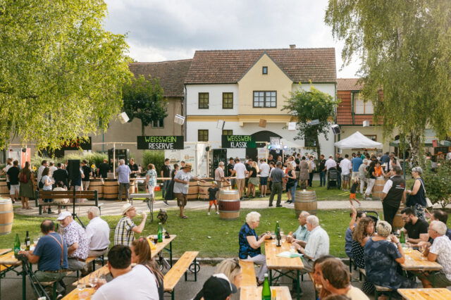 Menschen sitzen auf Bierbänken, trinken und essen beim Weinfest in Jois im Burgenland