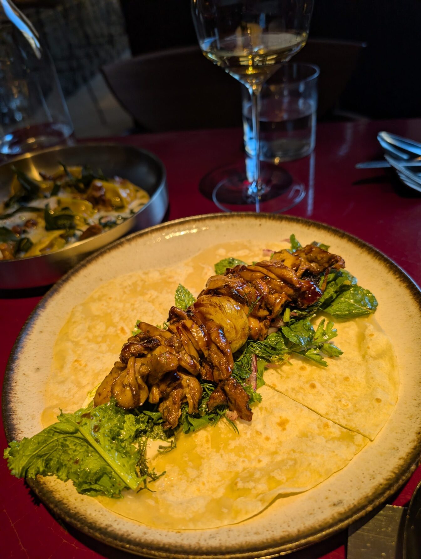 im Vordergrund steht ein Gericht, im Hintergrund ein Glas Wein auf einem Tisch im Restaurant Lara in Wien