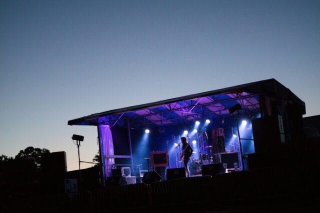 ein Mann steht vor dem Sonnenuntergang auf einer Bühne und gibt ein Konzert