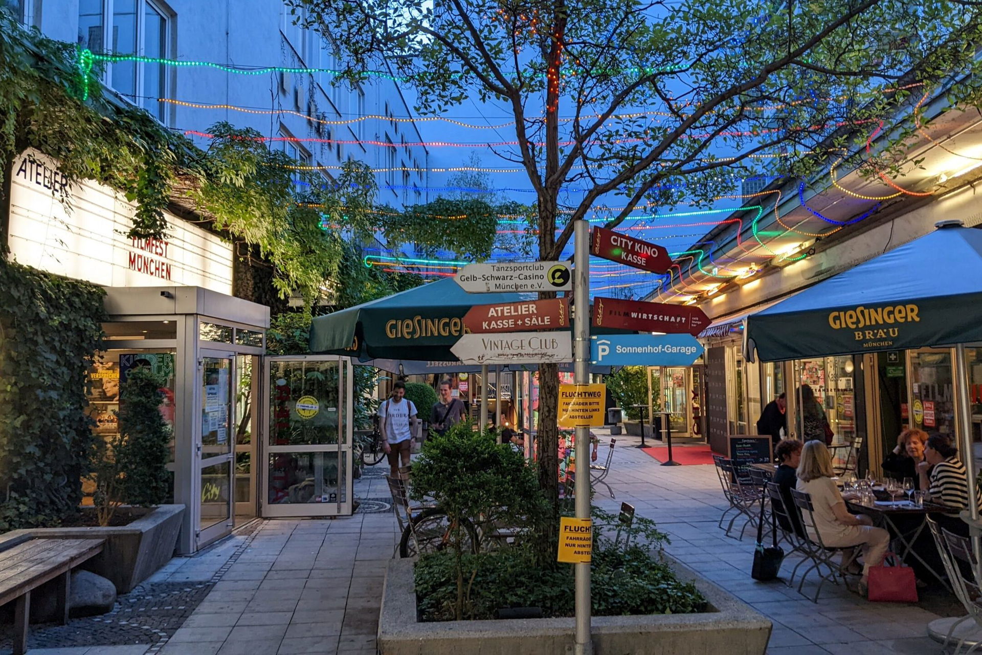 ein beleuchteter Innenhof mit vielen Schildern und Filmplakaten