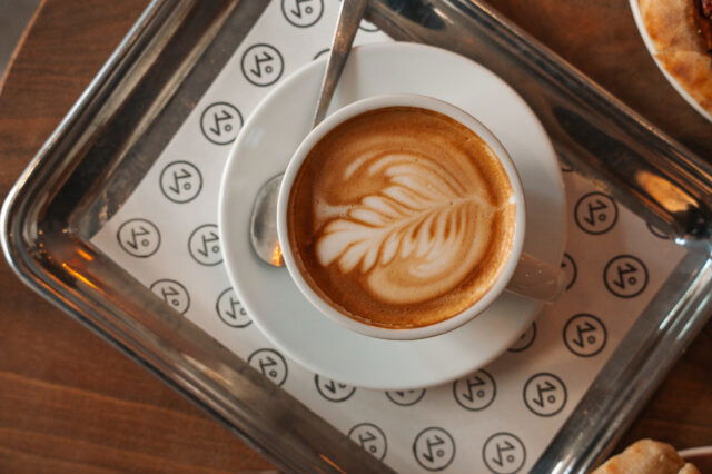 Café in München: Flat White mit Latte Art auf einem silbernen Tablett serviert.