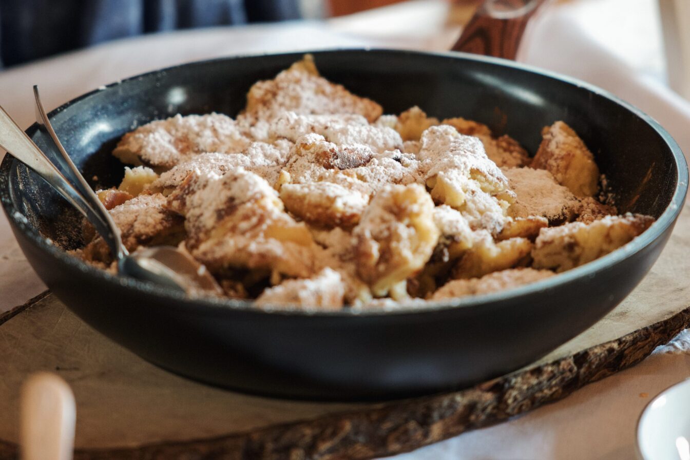 Frisch zubereiteter Österreichischer Kaiserschmarrn mit Puderzucker in einer Servierpfanne.