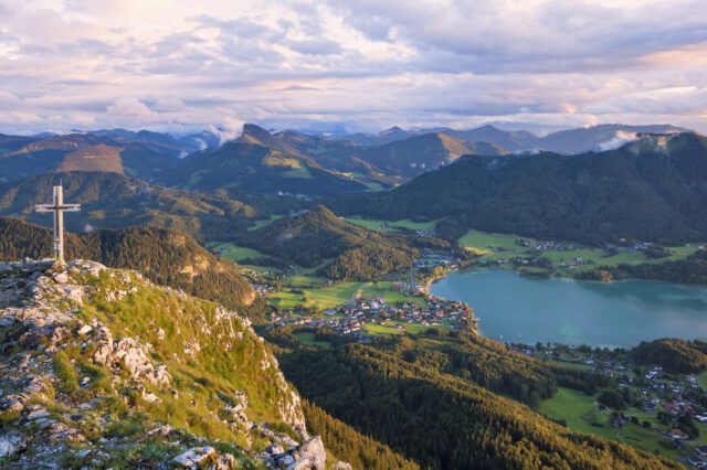 Der Gipfel des Frauenkopfs über Fuschl und dem Fuschlsee bei Sonnenuntergang, im Hintergrund die Osterhorngruppe