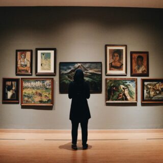 Frau in Museum vor Bildern (c) Unsplash | Zalfa Imani